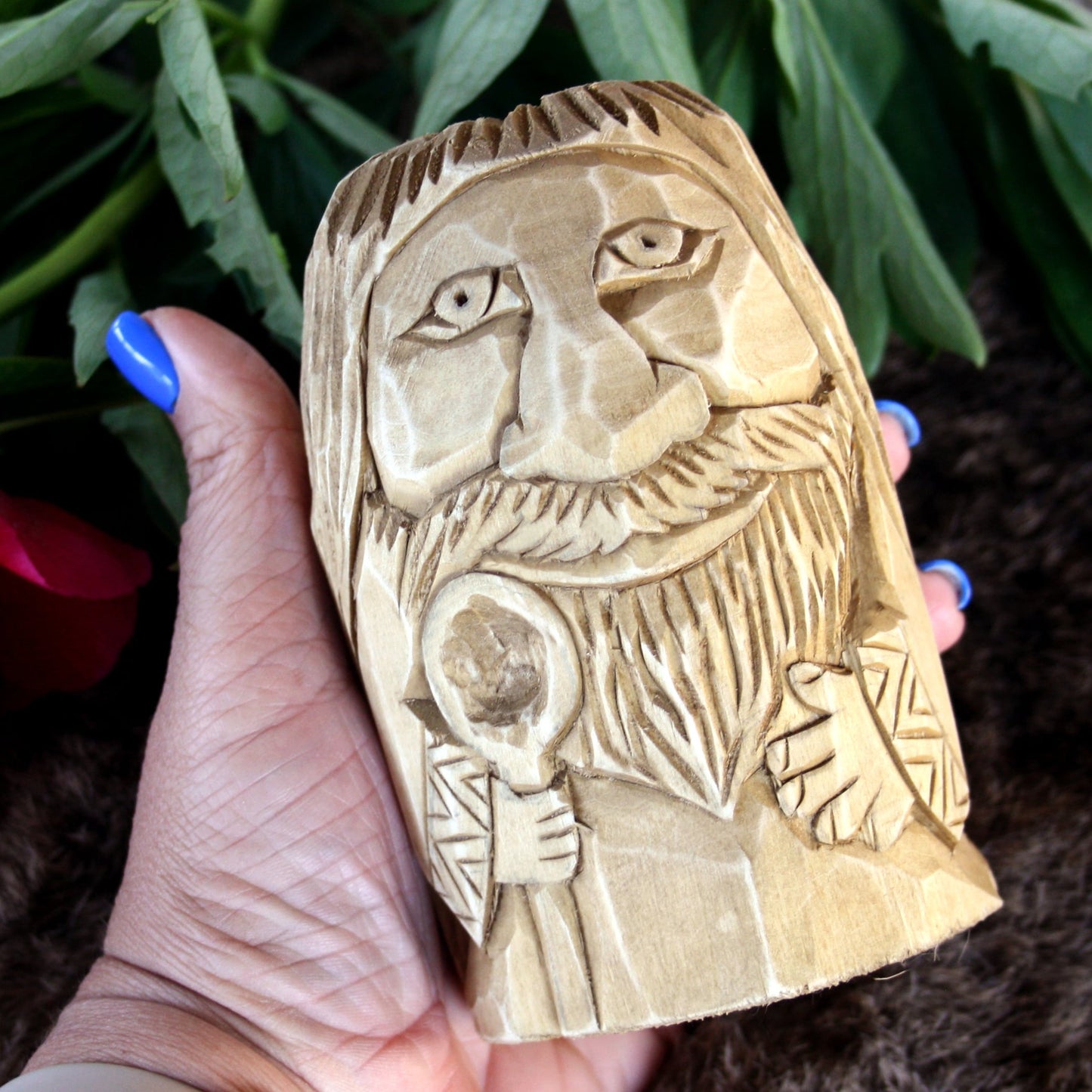 Hand holding a wooden carving of a Slavic Domovoi statue with spoon