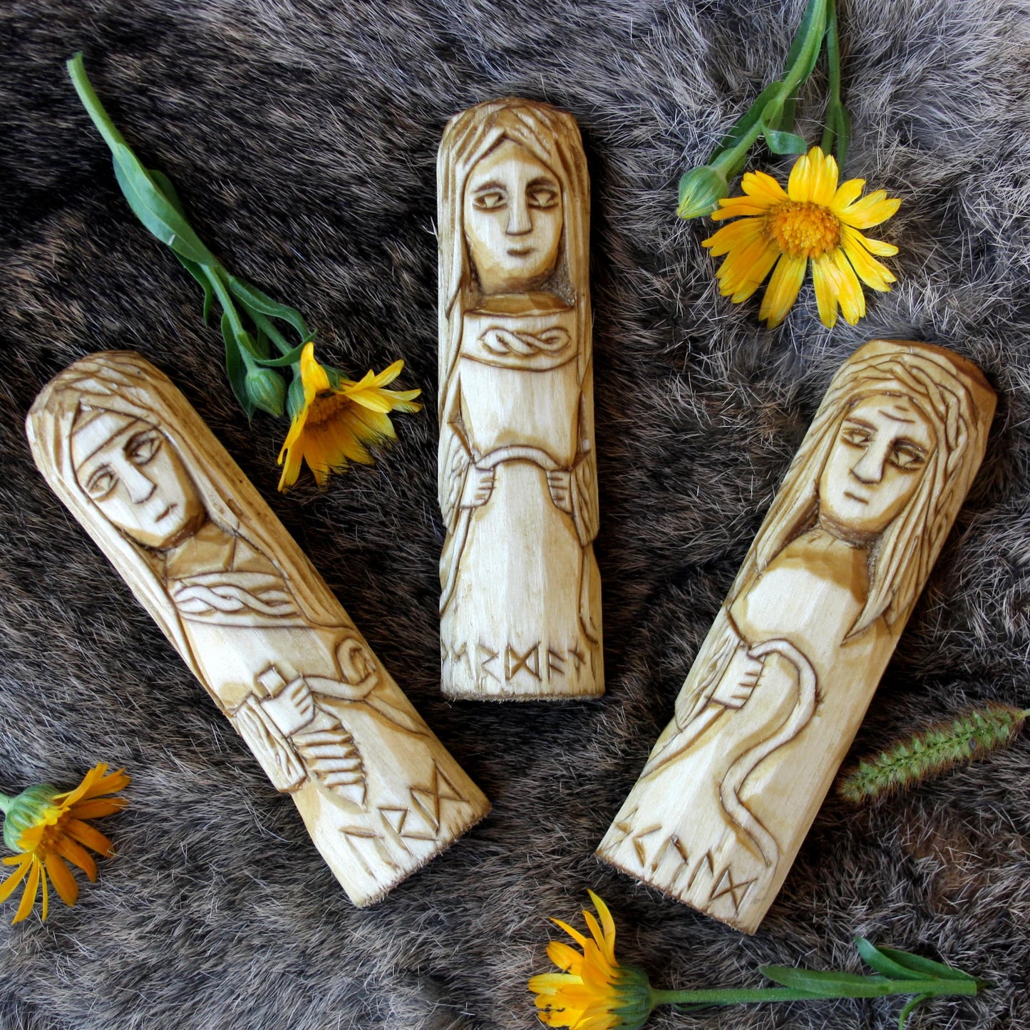 Norse Norns 10 cm wooden statues on a fur surface with yellow flowers.