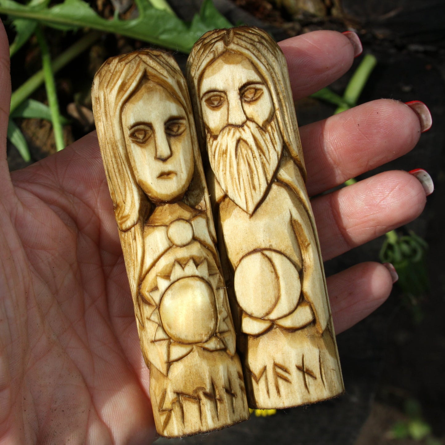 Sunna and Mani 10 cm wooden statues held in a hand with a natural background.