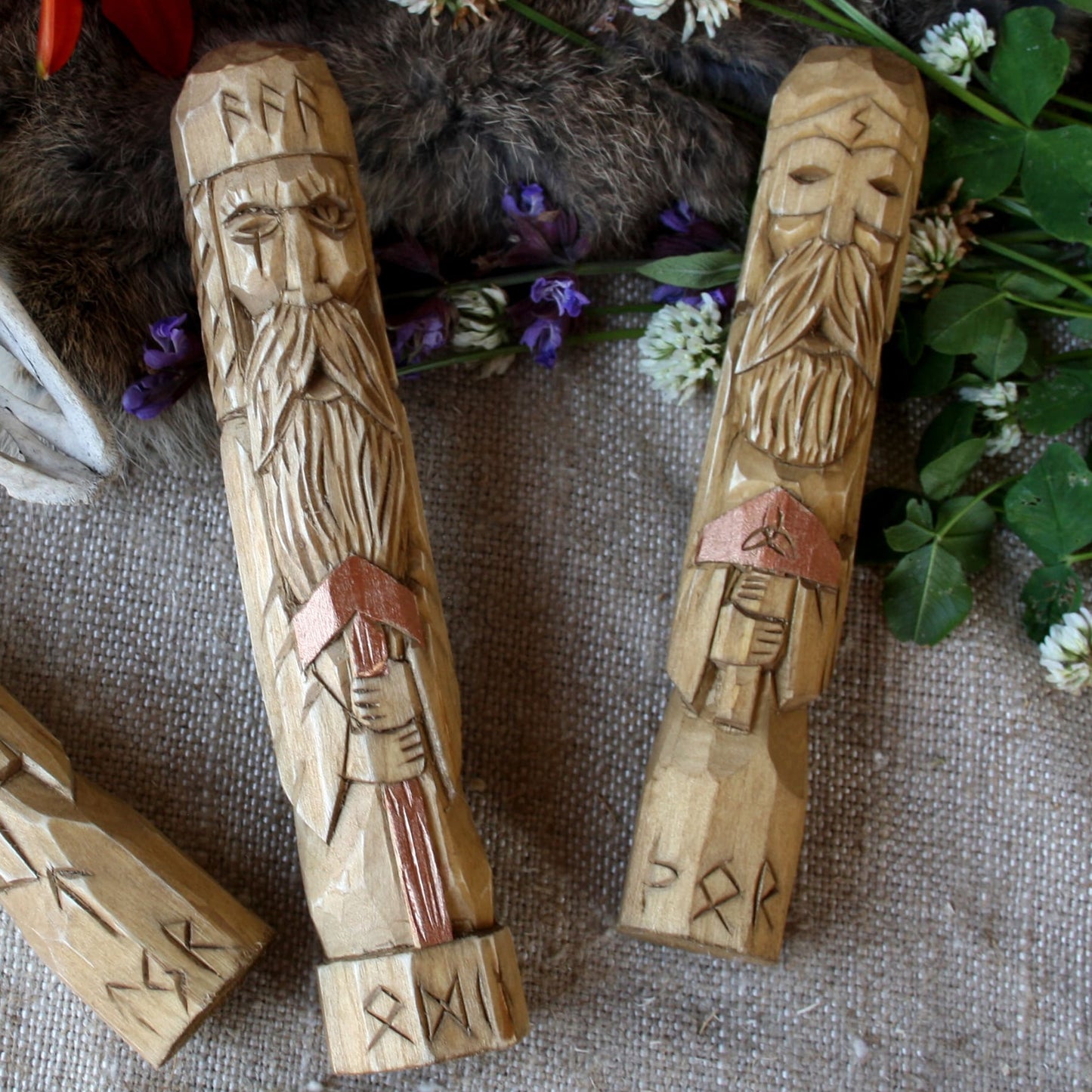 Hand carved Odin wooden statue resting on table with another Norse figurine