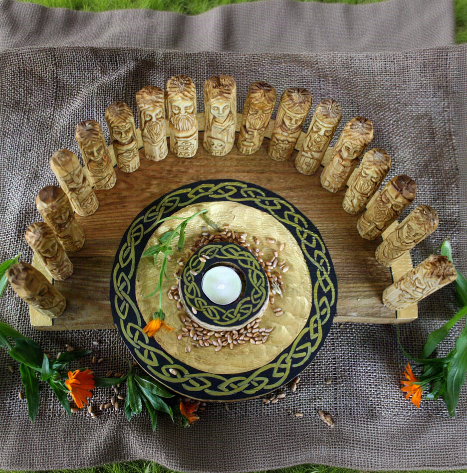 Overhead view of 17 Celtic god and goddess figurines arranged on a round decorative wooden altar