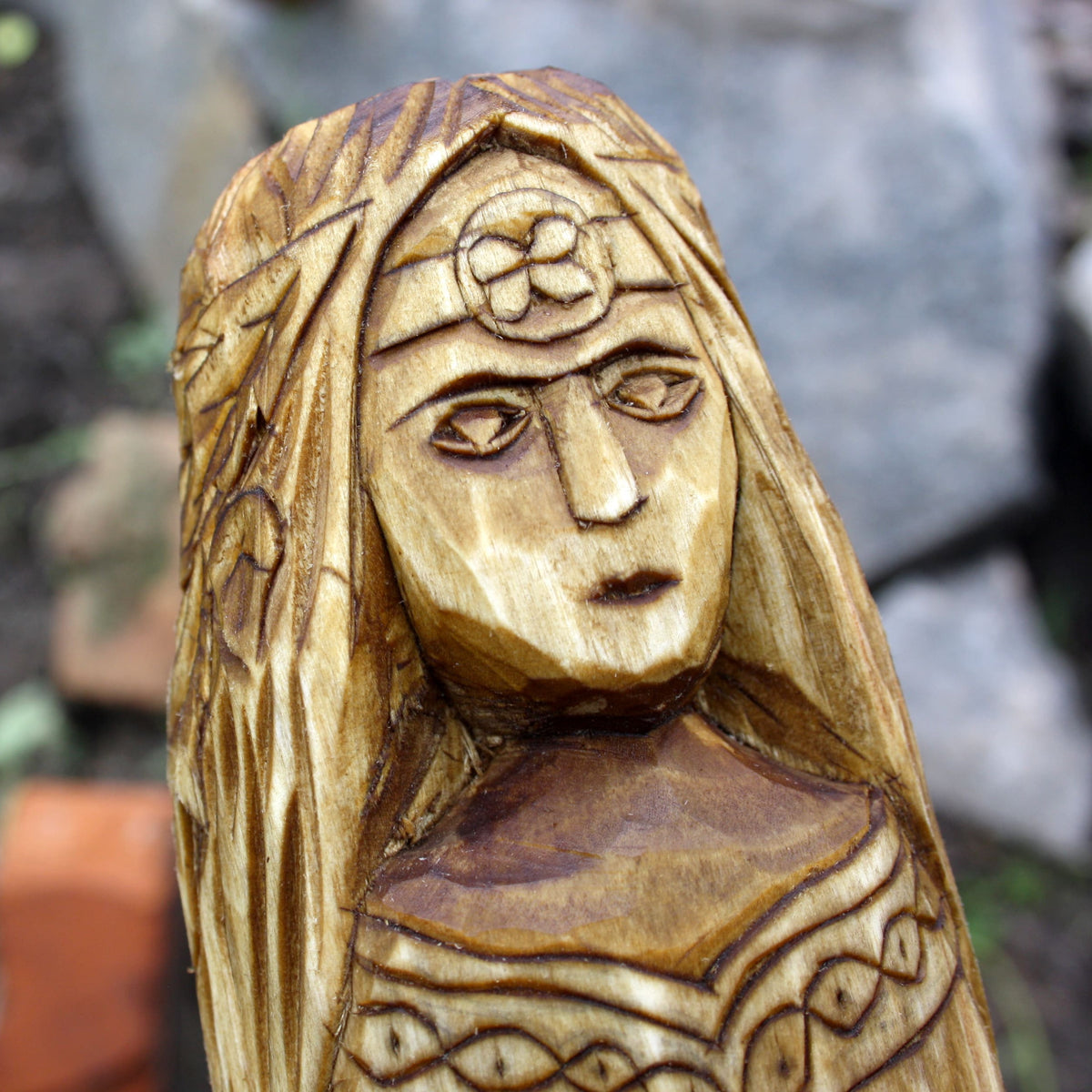 Close-up of Áine's carved face and long hair on the wooden Celtic goddess statue
