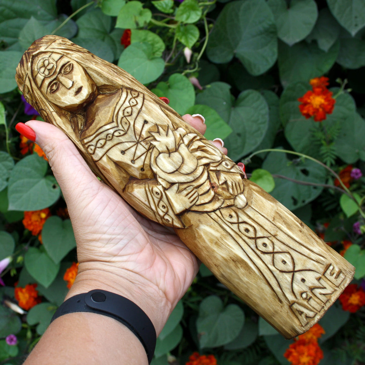 Hand holding the Áine wooden statue to show its size and sculptural details