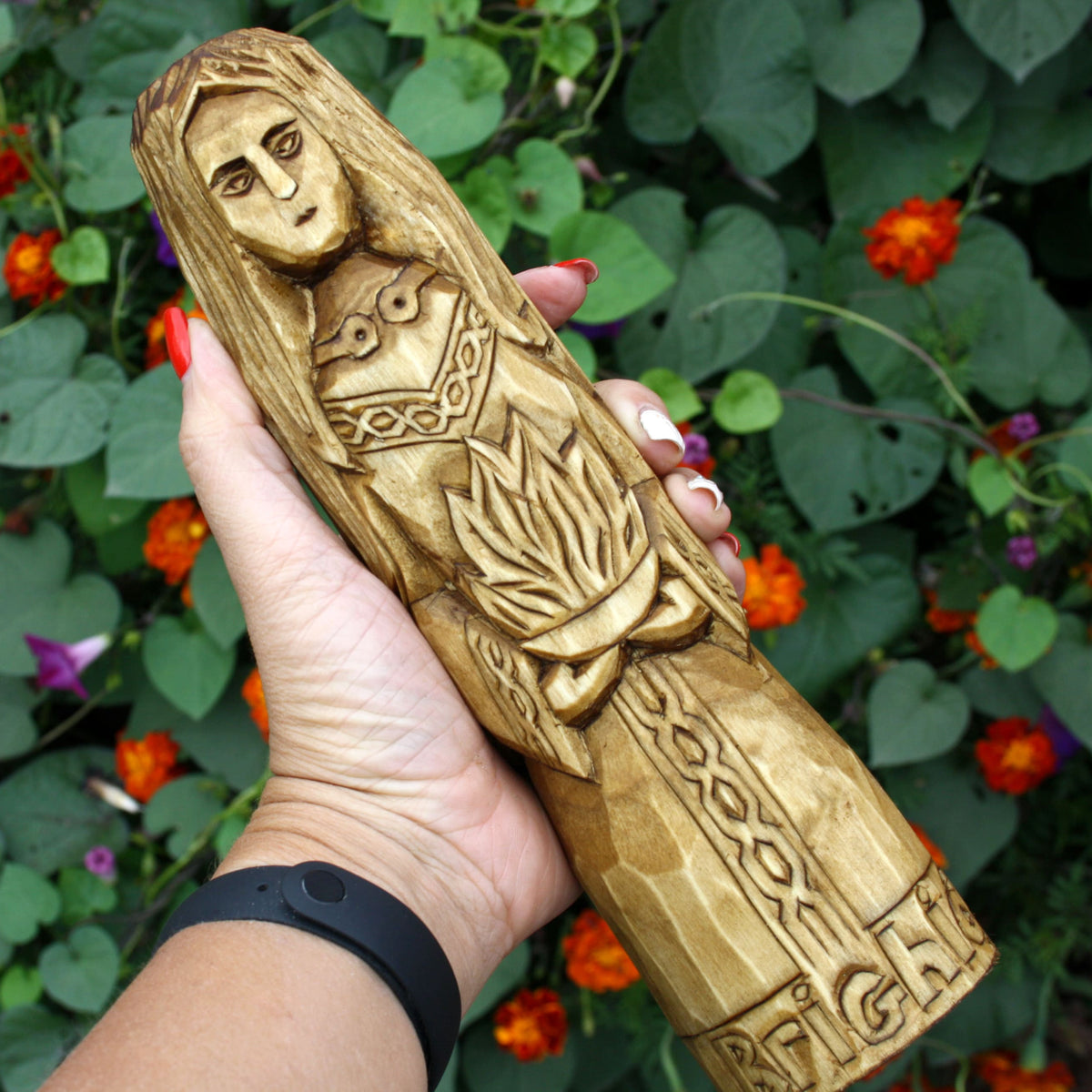 Hand holding the Brigid wooden statue to show its size and carved details