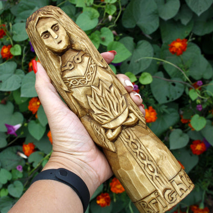 Hand holding the Brigid wooden statue to show its size and carved details