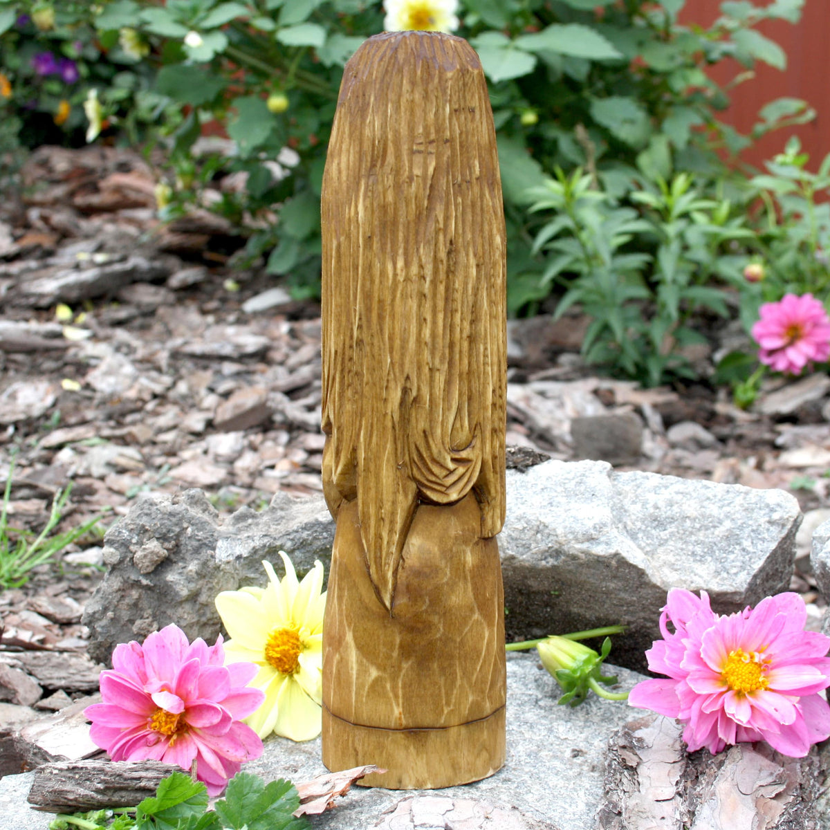 Back view of the hand-carved Brigid statue showing the natural wood grain