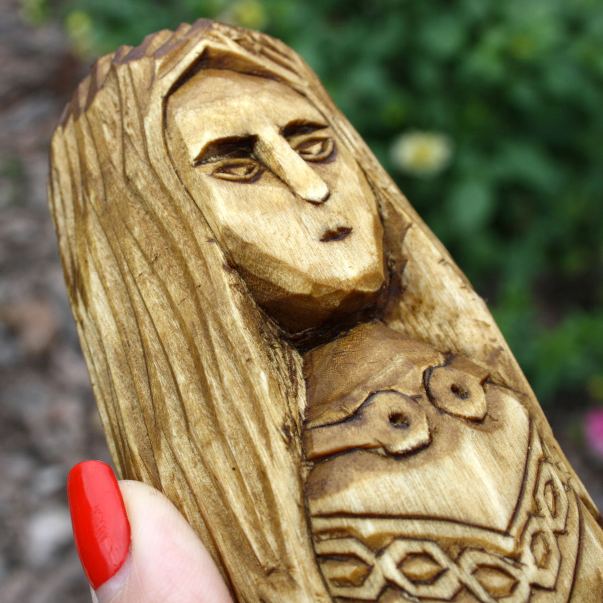 Close-up of Brigid's carved face and long hair on the wooden Celtic goddess statue