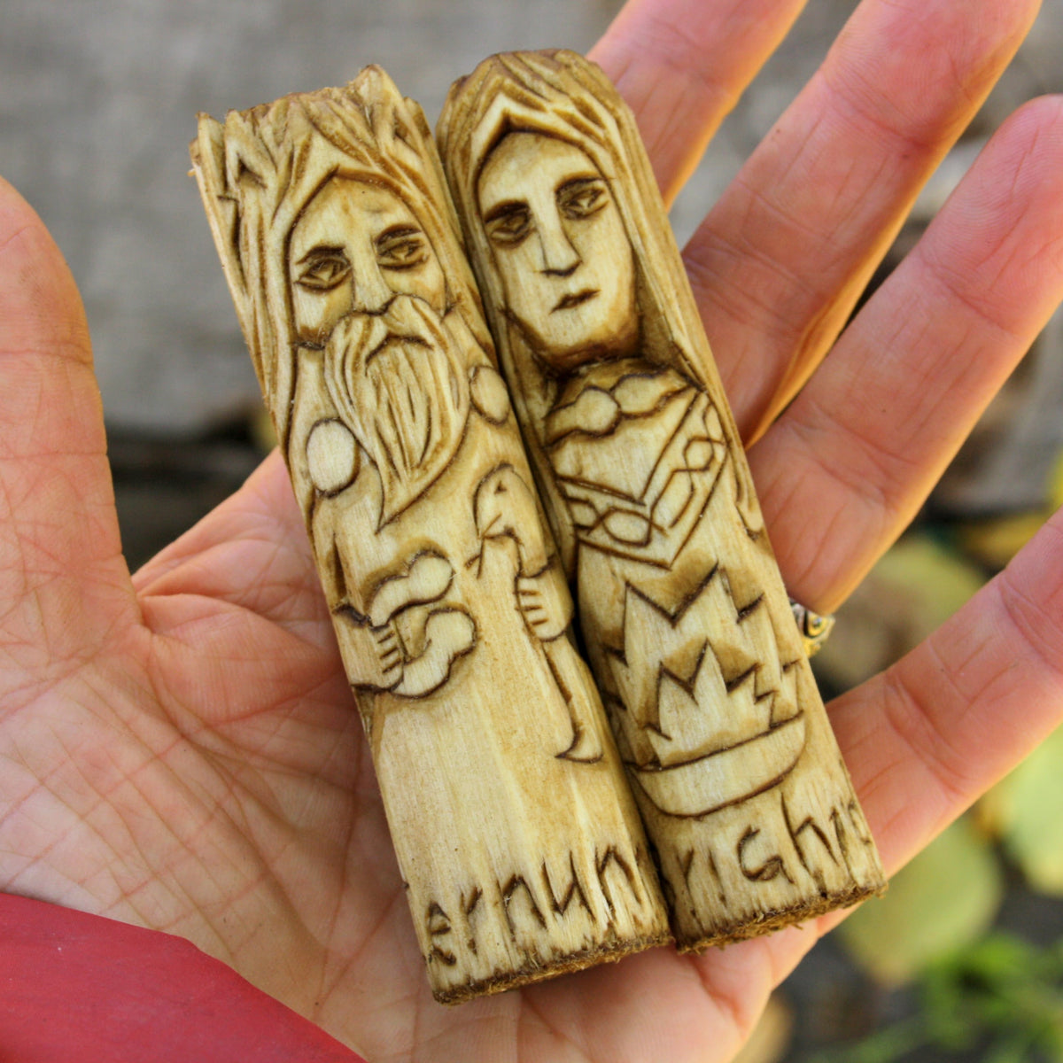 Two 10 cm Celtic wooden figurines held in a hand to show their compact size