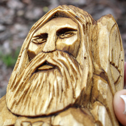 Close-up of Dagda's carved face, long beard, and flowing hair