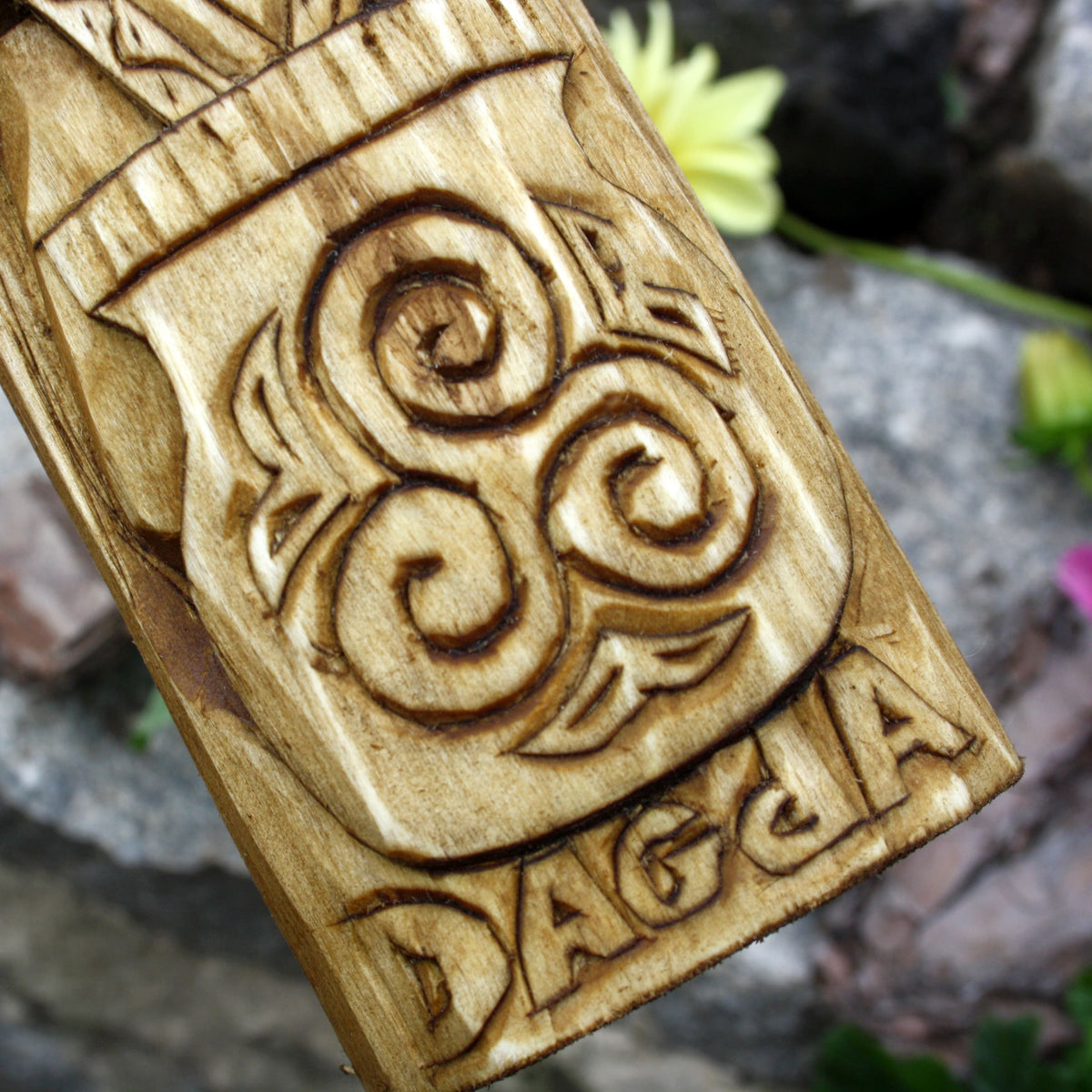 Close-up of the carved spiral motifs and decorative patterns on the Dagda statue base