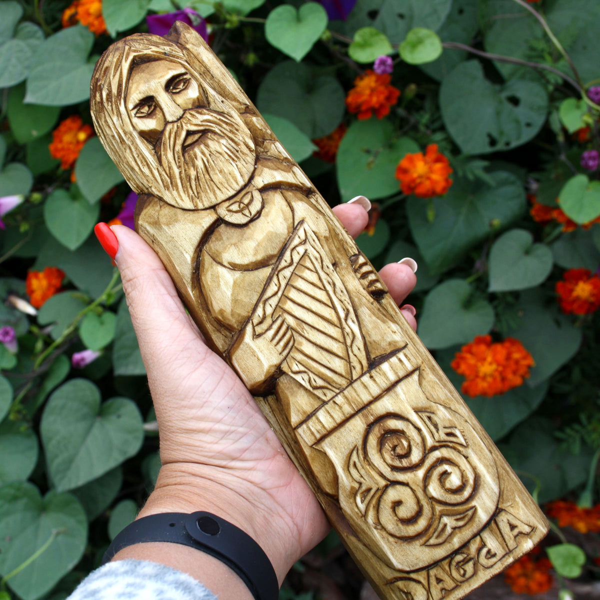 Hand holding the Dagda wooden statue to show its size and carved ornamental patterns