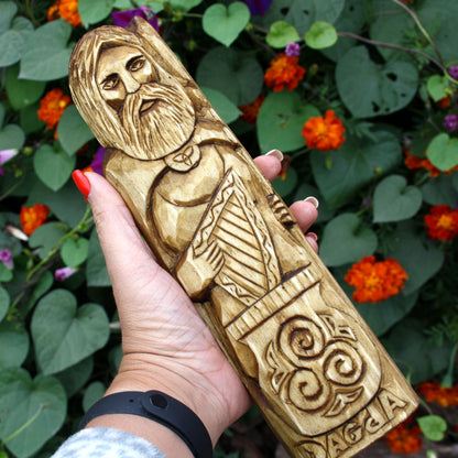 Hand holding the Dagda wooden statue to show its size and carved ornamental patterns