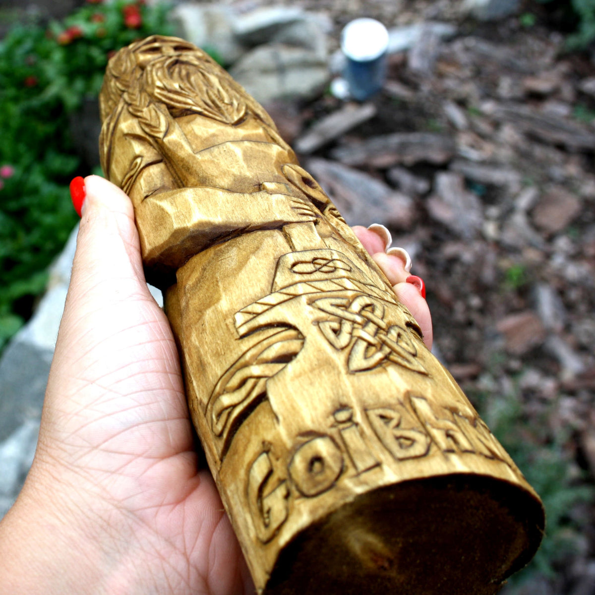 Goibhniu wooden sculpture resting on natural bark in a woodland-inspired setting