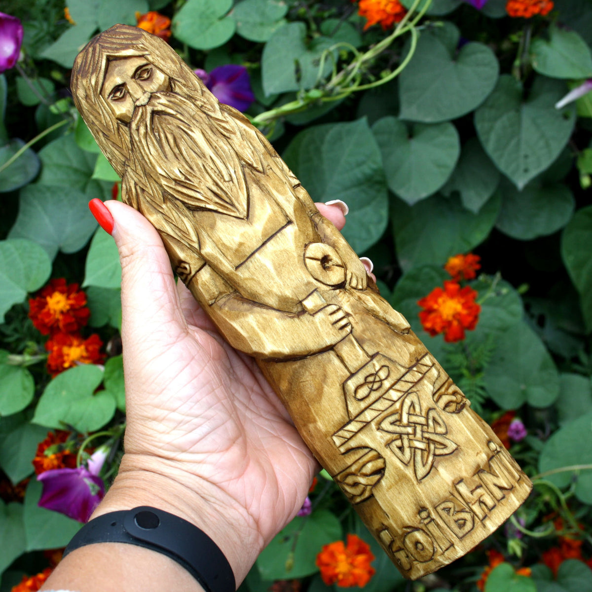 Hand holding the Goibhniu wooden statue to demonstrate its size and carved design
