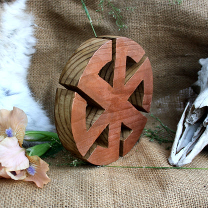 Angled view of hand carved wooden Kolovrat symbol made from linden wood