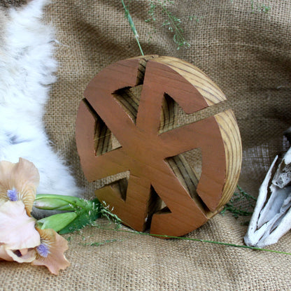Side view of handmade wooden Kolovrat Slavic symbol with bronze finish