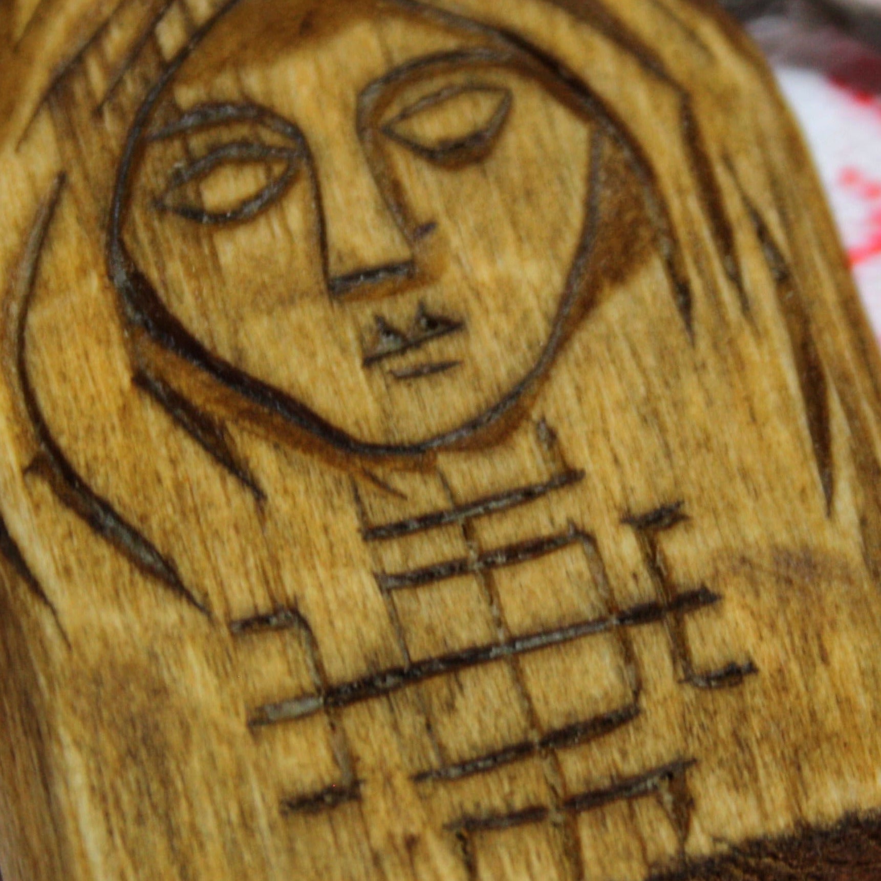Close-up of the carved Makosh goddess on a wooden pendant