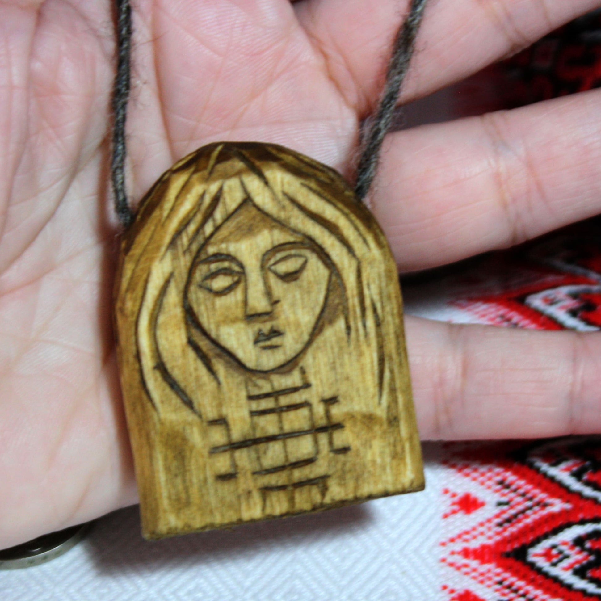Makosh wooden pendant held in hand showing its size