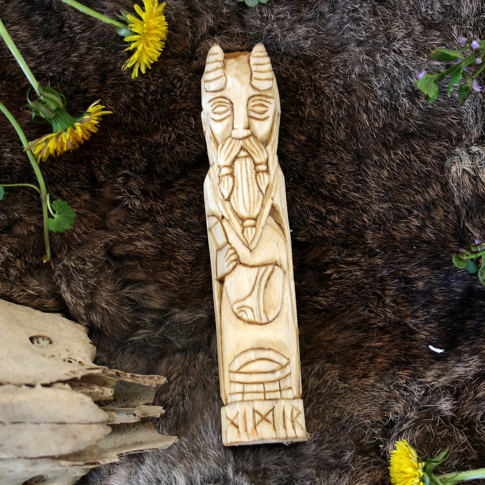 Mimir wooden statue 15 cm on a fur surface with yellow flowers and greenery