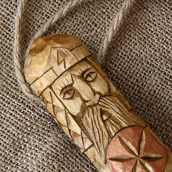 Close-up of the carved Perun symbol on a wooden amulet