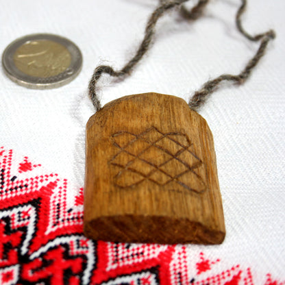 Back side of hand carved Svarog pendant made from natural linden wood