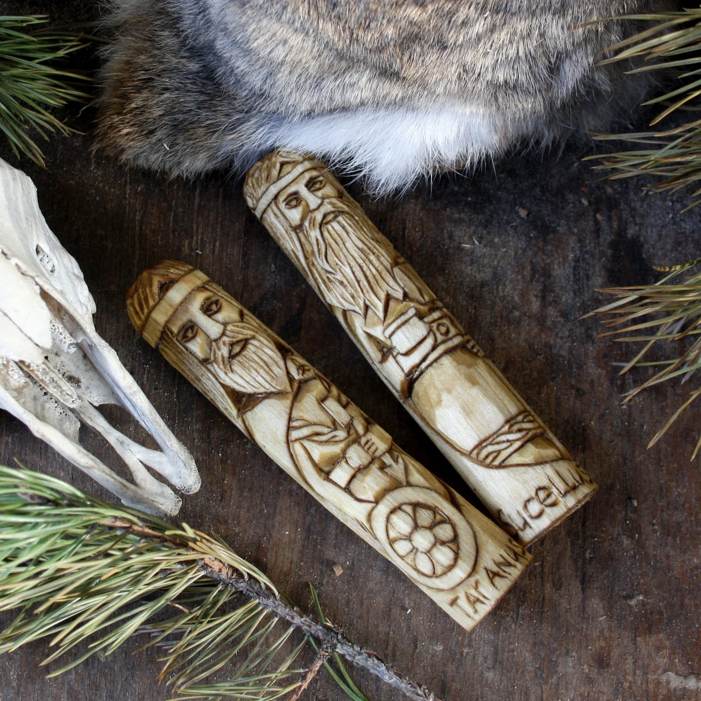 Taranus Celtic god of thunder 15cm hand-carved wooden statue displayed on a dark wooden surface with pine needles, a fur pelt, and a skull prop.