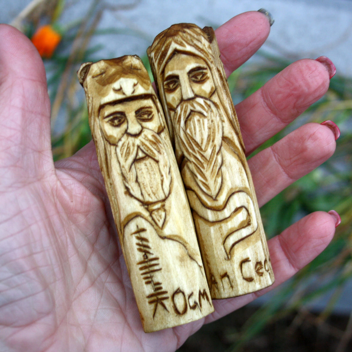 Two 10 cm hand-carved Celtic deity figurines held in a hand to show their size