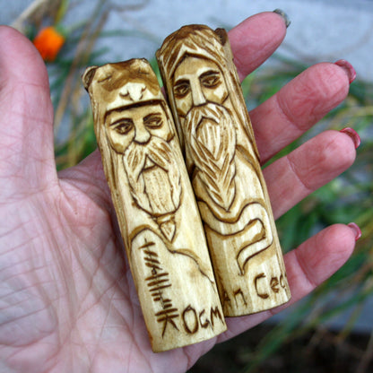 Two 10 cm hand-carved Celtic deity figurines held in a hand to show their size